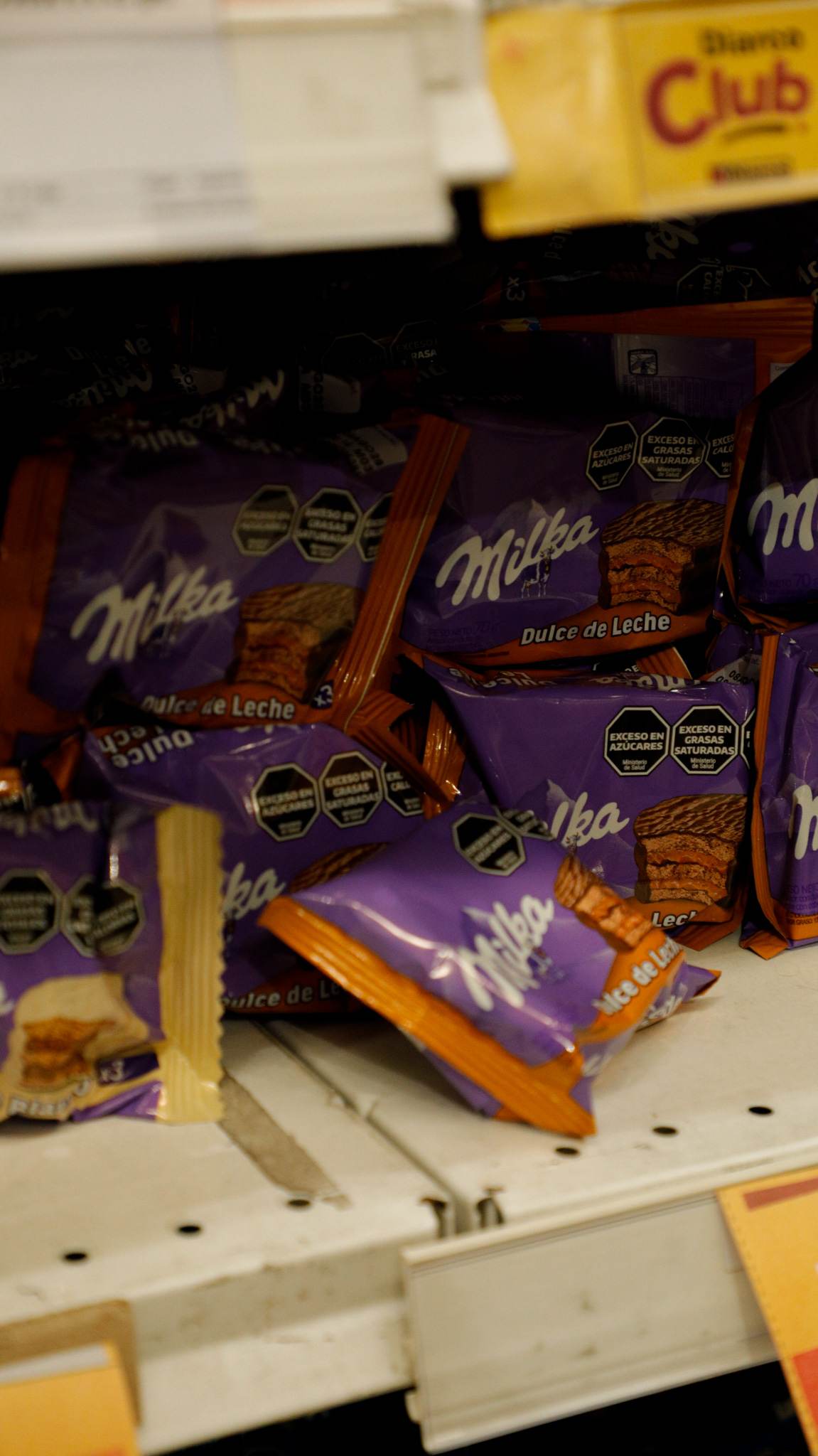 Estante de golosinas con paquetes de alfajores de una marca apilados y su cartel de precio.