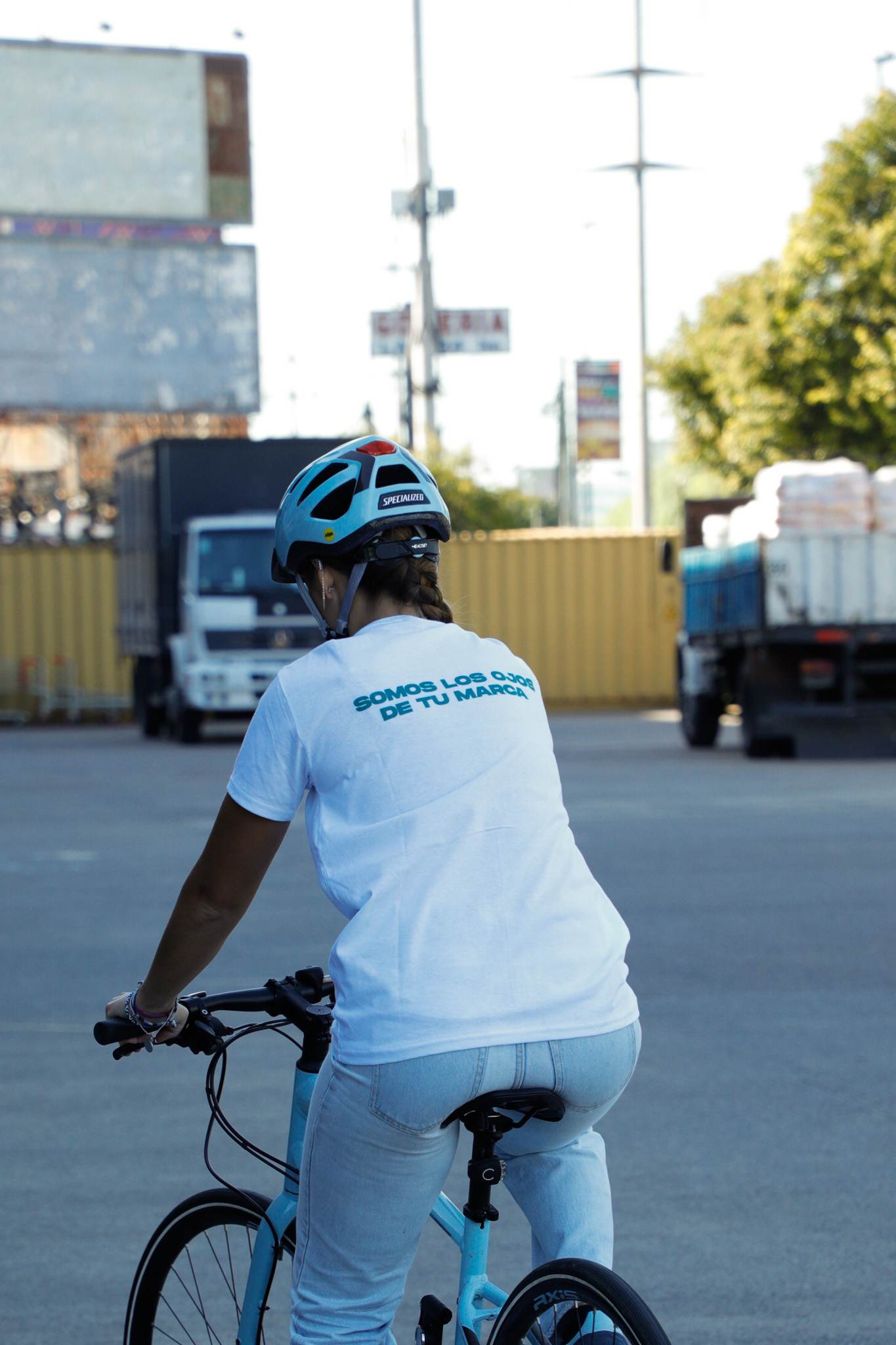 Znapper en bicicleta, de espaldas, con la leyenda Somos los ojos de tu marca en la remera.